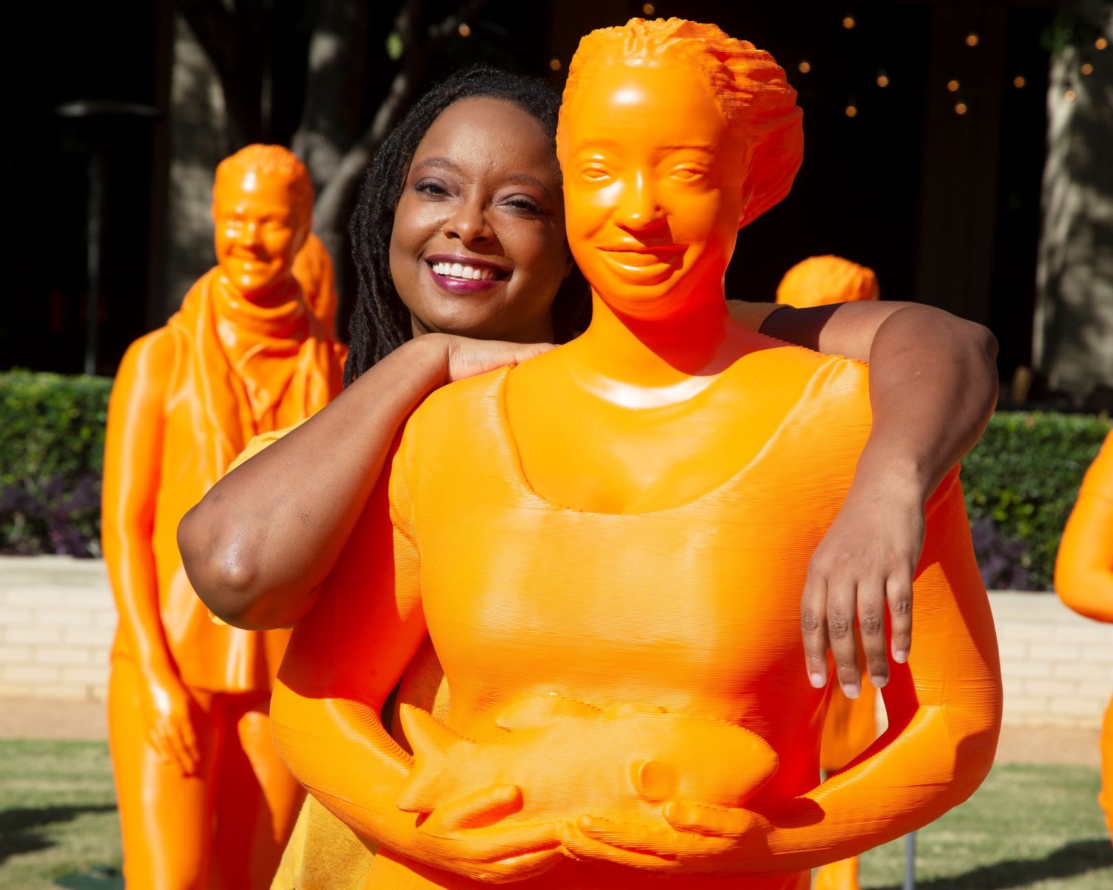 Kiki Jenkins standing with a life-sized orange statue of herself
