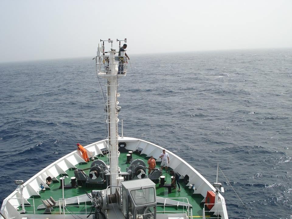 Image of Vernon Morris atop the forward Jackstaff of the NATO Alliance during a Saharan dust storm