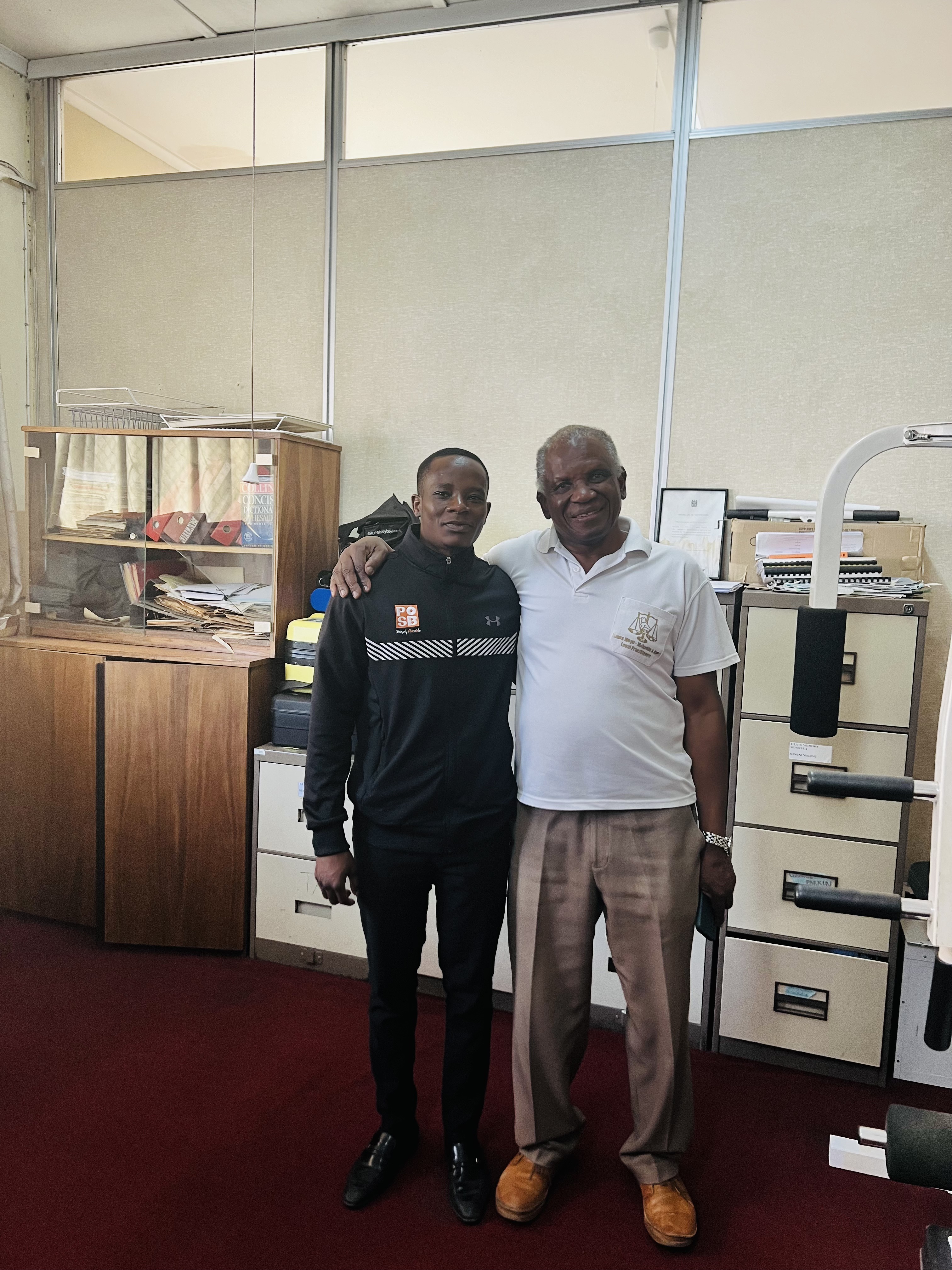 Mcebisi Moyo with legal mentor Mr. Richard Moyo-Majwabu in a professional office setting.