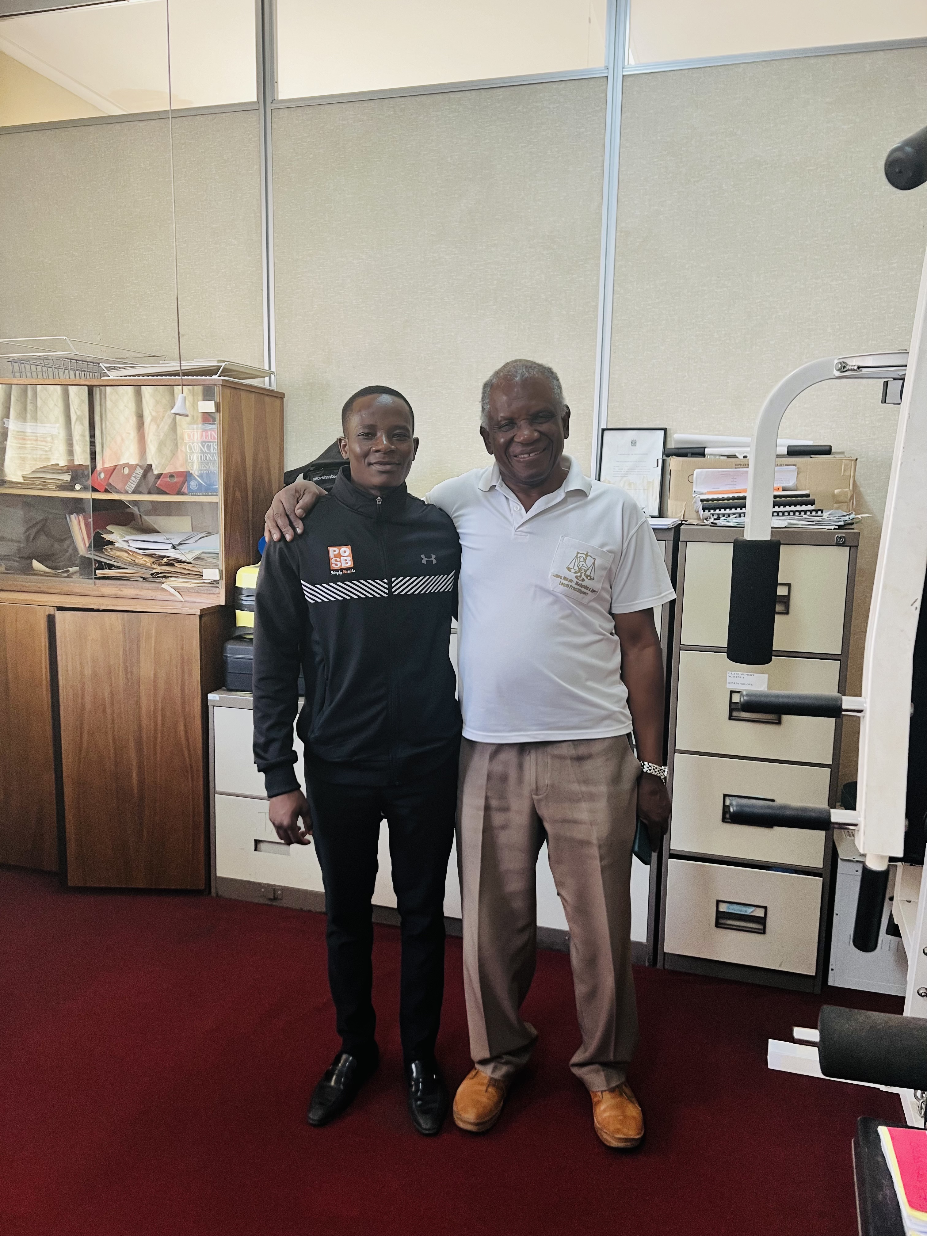 Mcebisi Moyo with legal mentor Mr. Richard Moyo-Majwabu in a professional office setting. 