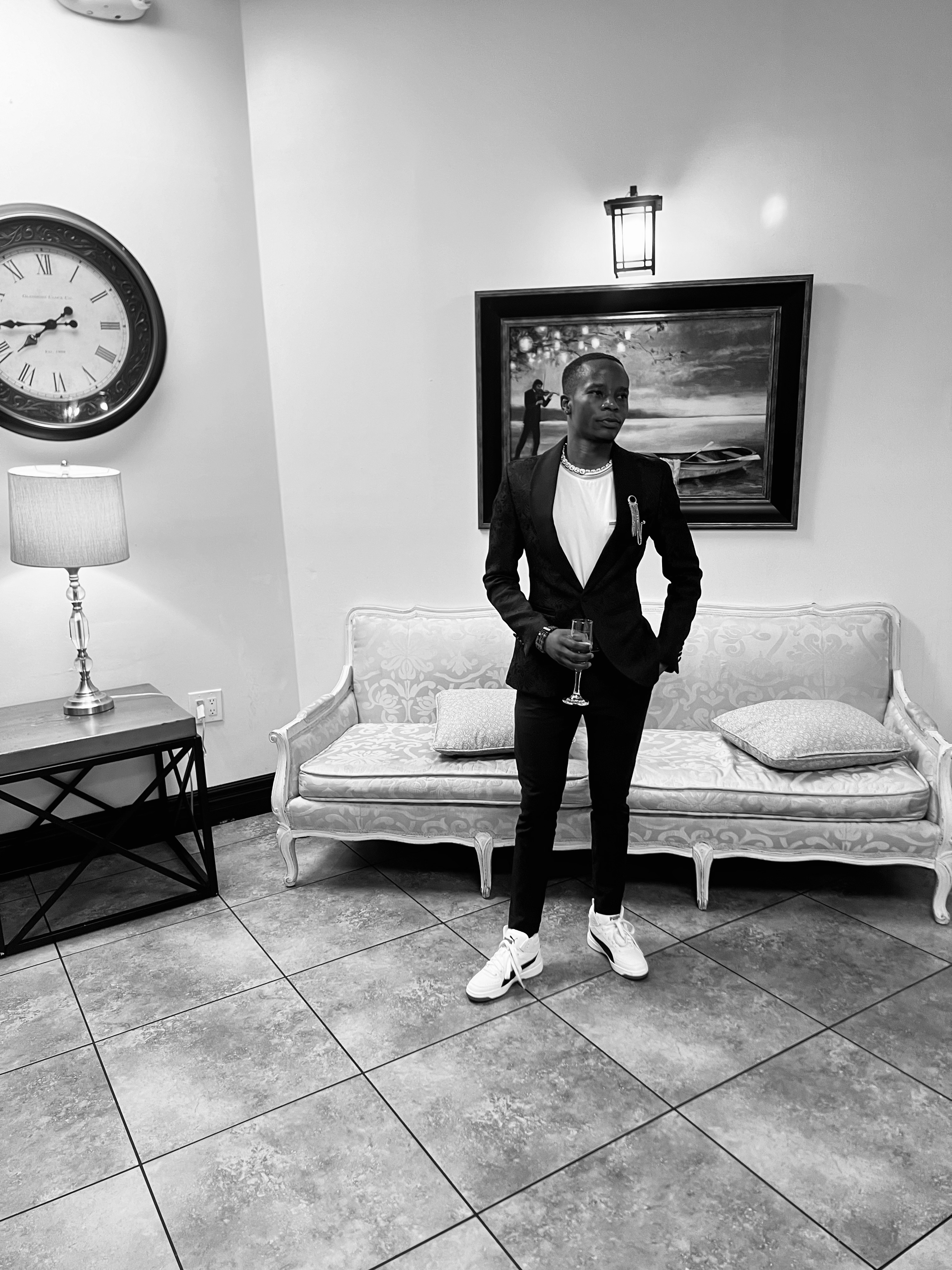 Mcebisi Moyo standing in formal attire in an indoor professional setting. 